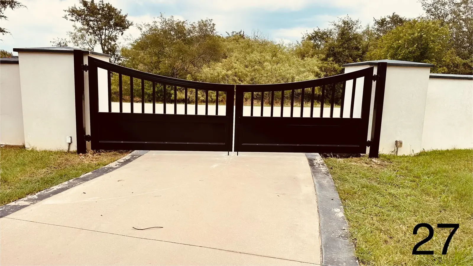 Black iron gate between stucco walls by Aesthetic Gates & Fence in Navarro County, Texas