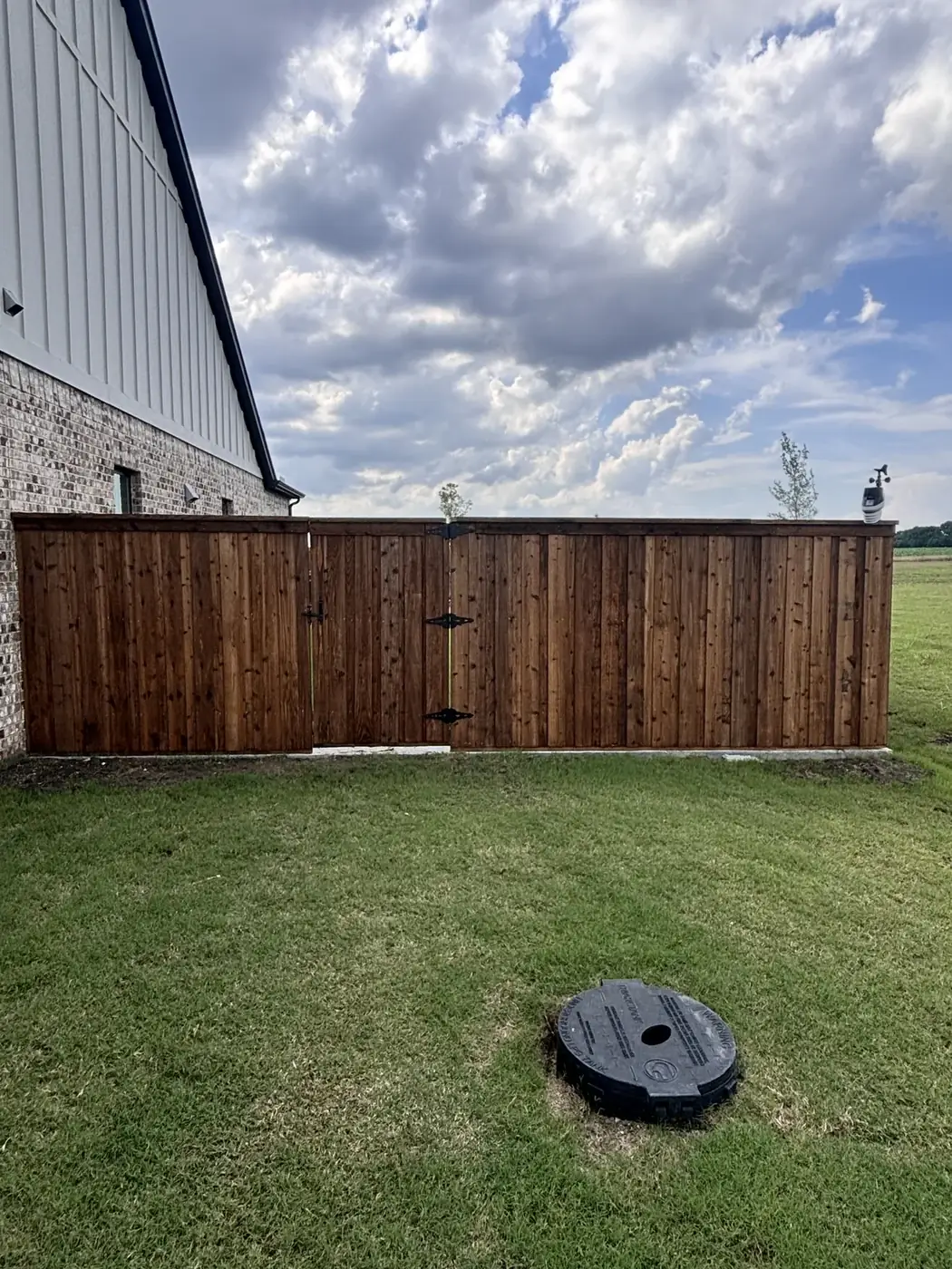 Cedar gate beside a metal roof by Aesthetic Gates & Fence in Navarro County, Texas