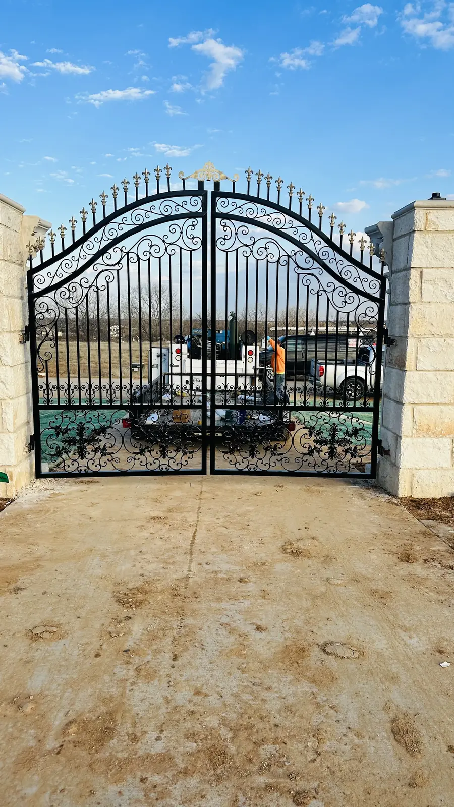 Arched iron and cedar driveway gate built by Aesthetic Gates & Fence in Corsicana, Texas