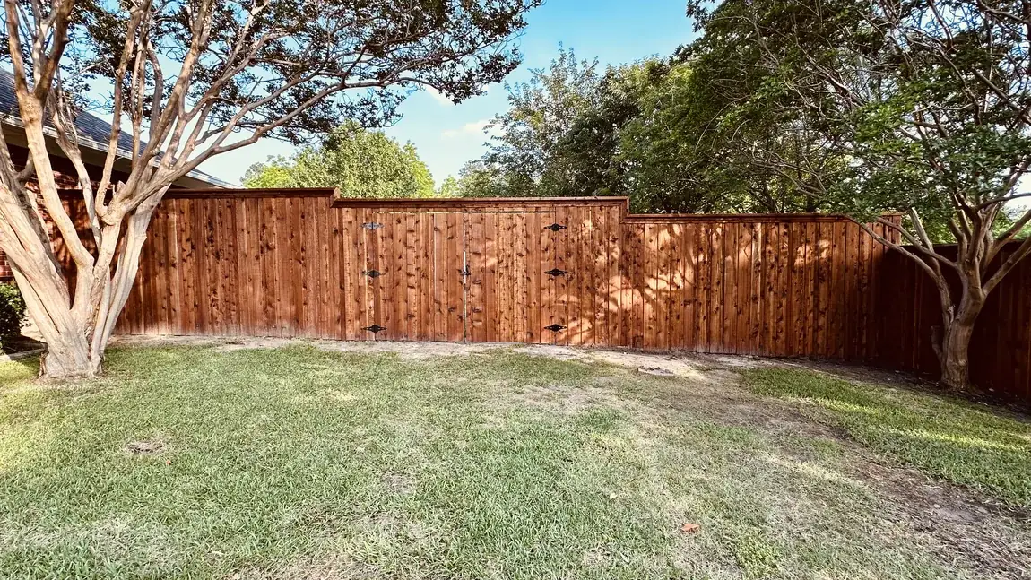 Wood fence behind crape myrtles by Aesthetic Gates & Fence in Navarro County, Texas
